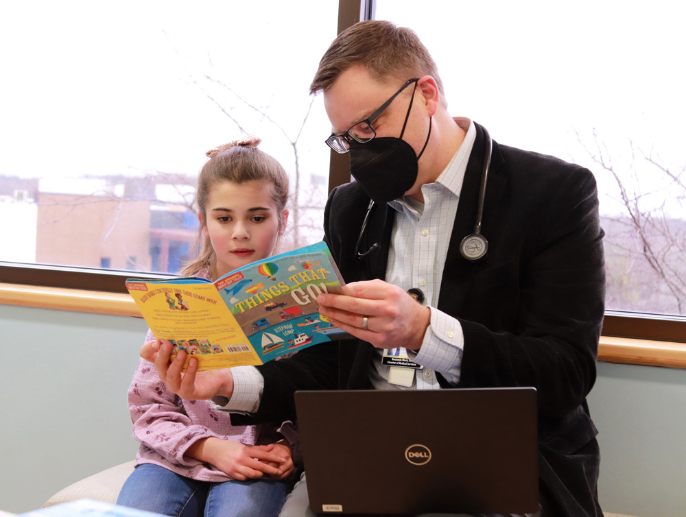 Doctor reading a book to a young girl.